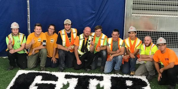 GTR Turf installation team posing together on a synthetic field during turf installation project with safety gear and uniforms