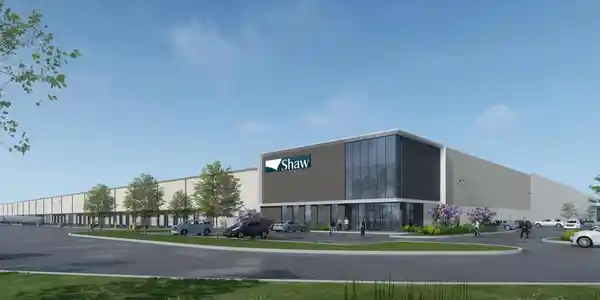 Modern synthetic turf manufacturing facility building exterior with corporate branding and landscaped surroundings